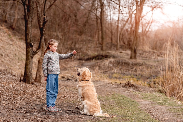 Preteen girl jouant avec un chien golden retriever sur la nature au printemps