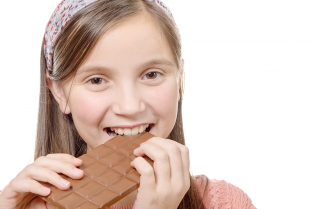 Preteen girl mange du chocolat, isolé sur blanc