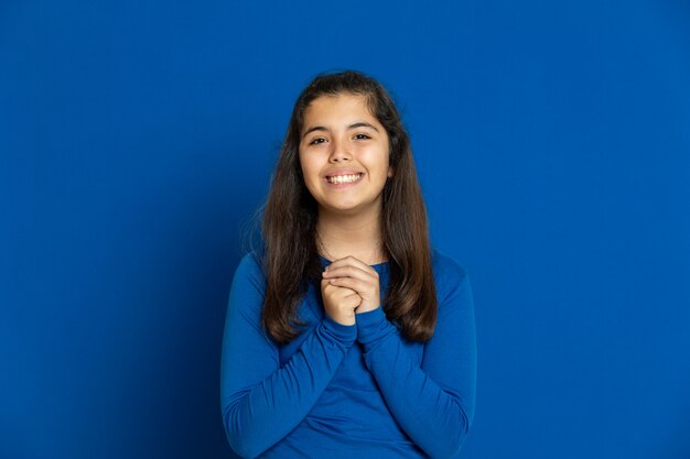 Preteen girl with blue jersey gesticulant sur mur bleu