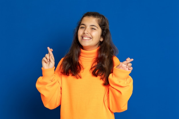 Preteen girl with yellow jersey gesticulant sur mur bleu