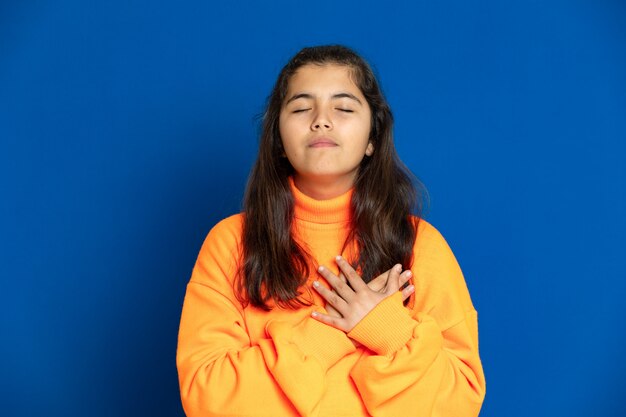 Preteen girl with yellow jersey gesticulant sur mur bleu