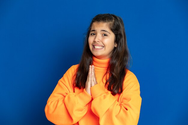 Preteen girl with yellow jersey gesticulant sur mur bleu