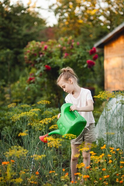 Preteenage girl avec un arrosoir dans le jardin