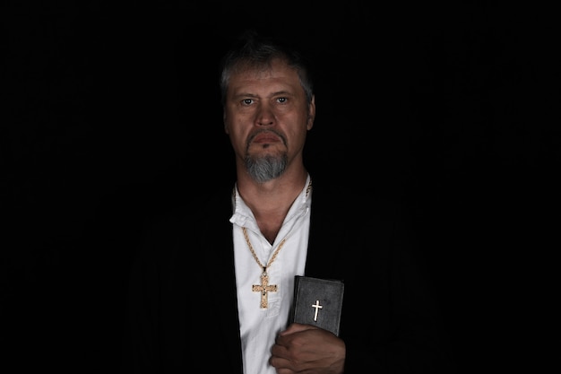 prêtre avec la bible sur fond noir