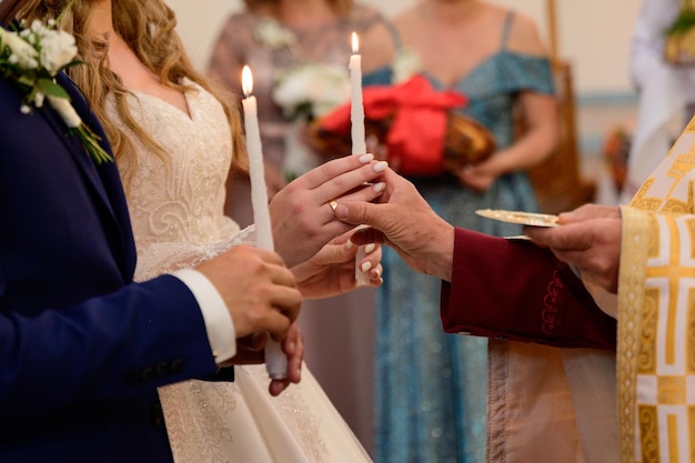 Le prêtre donne aux mariés des bougies allumées dans ses mains