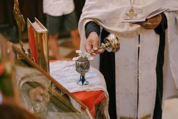 Le prêtre préside le service tenant la bible et la croix dans sa main