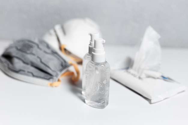 Prévention du Corona virus. Deux bouteilles de gel antiseptique désinfectant près de masques médicaux contre la grippe et de lingettes humides sur tableau blanc. Vue de dessus.