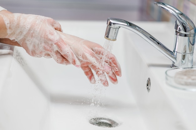 Prévention du coronavirus. Se laver les mains avec du savon antibactérien et de l'eau chaude courante en frottant les ongles et les doigts dans l'évier