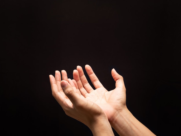 Prier les mains sur le fond sombre avec la foi en la religion et la croyance en Dieu.