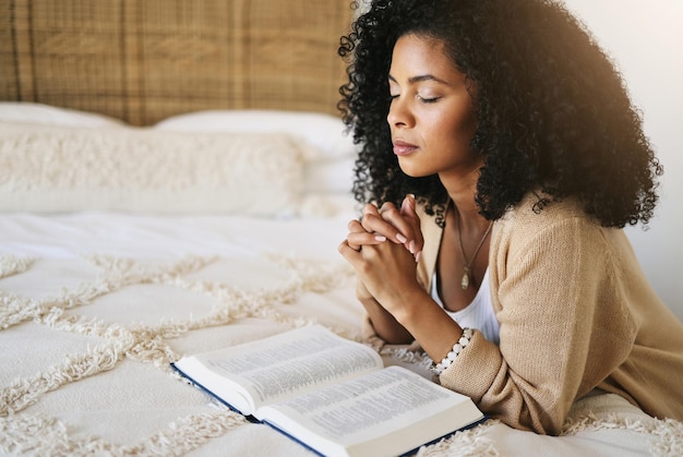 Prière biblique et femme noire priant sur le lit dans la chambre à coucher pour l'espoir, l'aide ou la foi spirituelle Dieu culte chrétien et féminin Jésus ou Saint-Esprit pour le pardon compassion ou grâce dans la maison