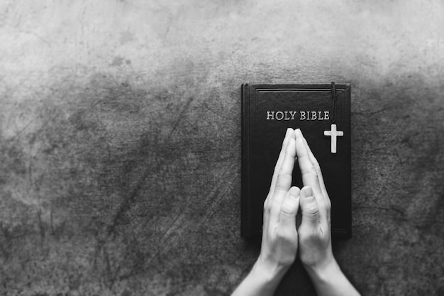 La prière chrétienne et l'adoration avec les mains jointes sur la croix et la sainte Bible