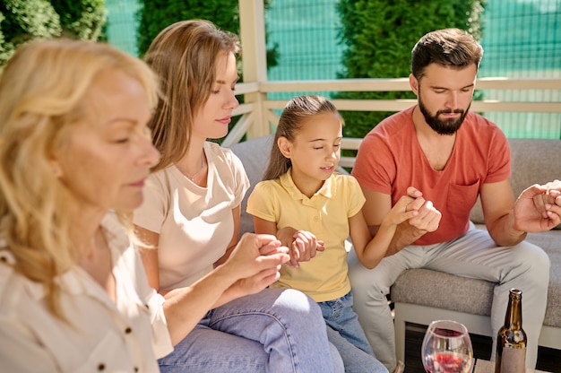 Prière du dîner. Une famille assise les yeux fermés et priant ensemble avant le dîner