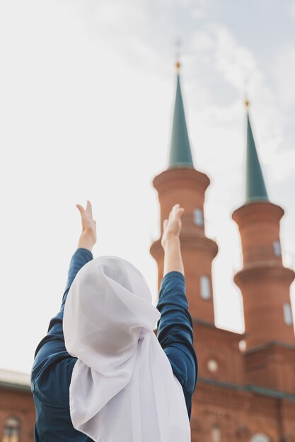 La prière d'une femme musulmane porte le hijab le jeûne prie à allah sur la vue arrière de la mosquée