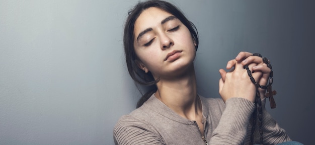 Prière jeune femme tenant une croix en bois