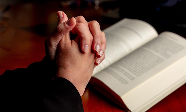 Priez Dieu main féminine en prière sur une table en bois de la Sainte Bible vue rapprochée