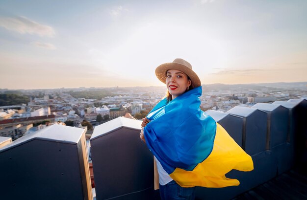 Priez pour l'UkrainexAA femme se tient avec le drapeau national ukrainien et l'agite en priant pour la paix au coucher du soleil à LvivxAA symbole de l'indépendance et de la force du peuple ukrainien