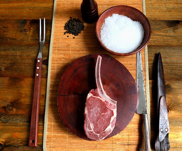 Prime Rib Raw Rib Eye steak avec os pour barbecue sur fond de bois