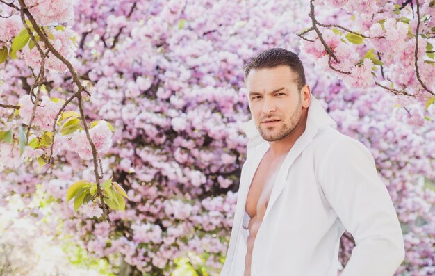 Printemps bel homme fleur de sakura rose printemps homme barbu en chemise blanche mode masculine