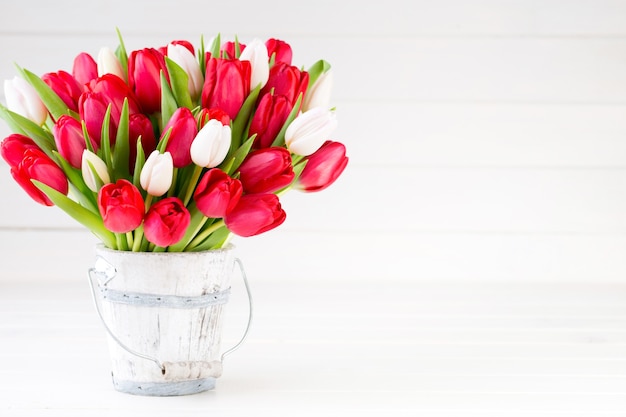 Le printemps. Bouquet de tulipes rouges sur fond en bois blanc.