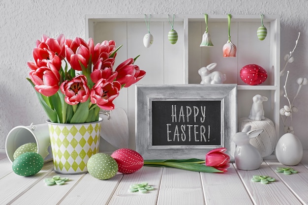 Printemps avec des décorations de Pâques et un tableau noir. Vitrine avec différents objets et tulipes roses