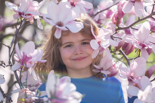 Le printemps est un moment de plaisir pour les enfants. Les enfants jouent à l'extérieur dans un magnifique jardin de printemps. Le visage de l'enfant dans les fleurs est adorable.