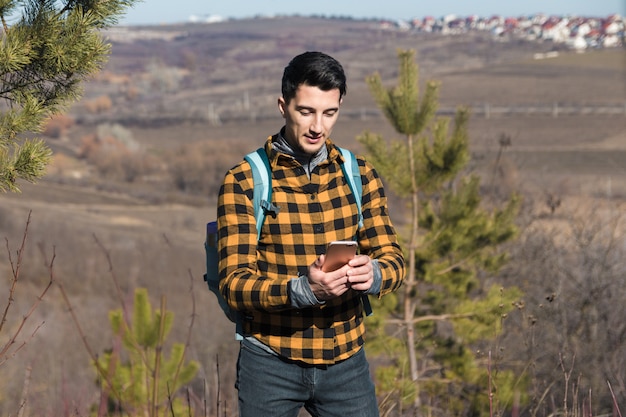 Printemps à l'extérieur. bel homme dans la campagne à l'aide de téléphone pour naviguer