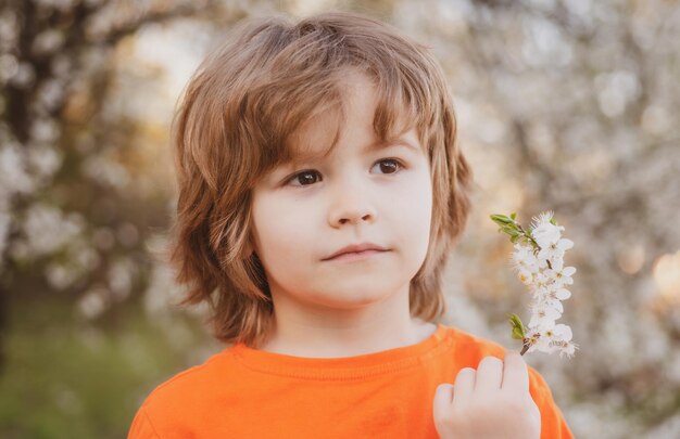 Printemps garçon enfant enfant dans un parc fleuri enfance heureuse et adaptation aux enfants