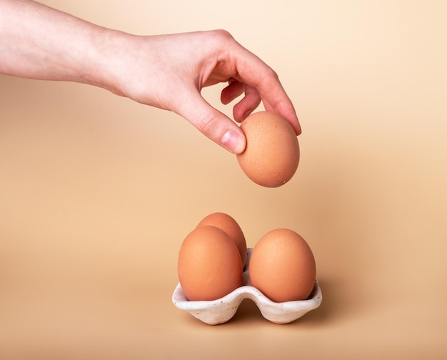 Prise à la main d'un œuf de poule sain dans une coquille d'œuf à partir d'un support en céramique