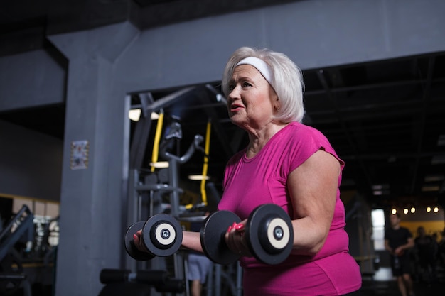 Prise De Vue En Angle Bas D'une Femme âgée Faisant Des Boucles De Biceps Avec Des Haltères