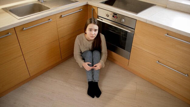 Photo prise de vue en pov d'une adolescente assise par terre et se cachant de l'agression et de la violence