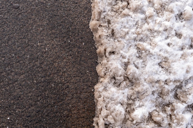 Une prise de vue rapprochée de la neige boueuse sur une route d'asphalte