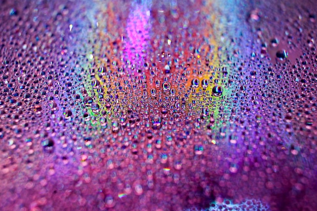 Photo prise de vue sélective de gouttes d'eau réfléchissantes colorées sur une surface de disque numérique