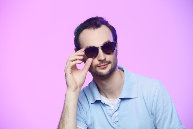 Prise de vue en studio d'un bel homme portant des lunettes de soleil sur fond rose