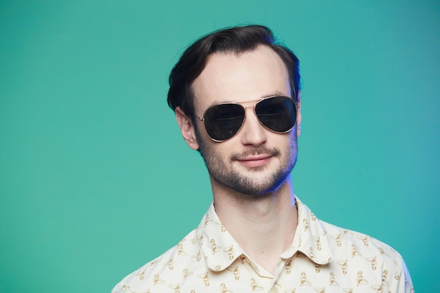 Prise de vue en studio d'un bel homme portant des lunettes de soleil sur fond vert