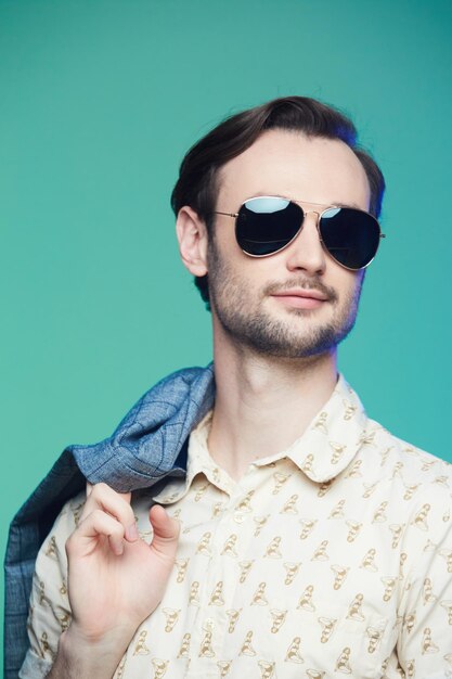 Prise de vue en studio d'un bel homme portant des lunettes de soleil sur fond vert