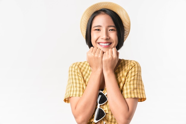 Photo prise de vue en studio d'une belle femme asiatique joyeuse debout et portant un chapeau sur fond jaune