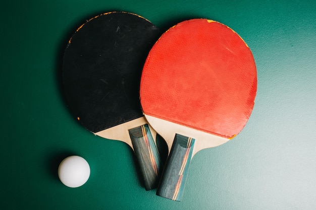 Prise de vue en studio de deux raquettes de ping-pong et d'une balle sur la table de jeu verte