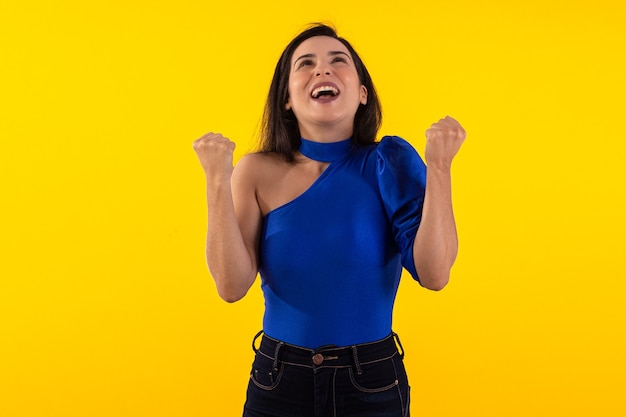 Prise de vue en studio d'une jeune femme à lunettes avec un chemisier bleu sur fond jaune avec une expression faciale