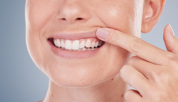 Prise de vue en studio d'une jeune femme méconnaissable montrant ses dents sur un fond gris