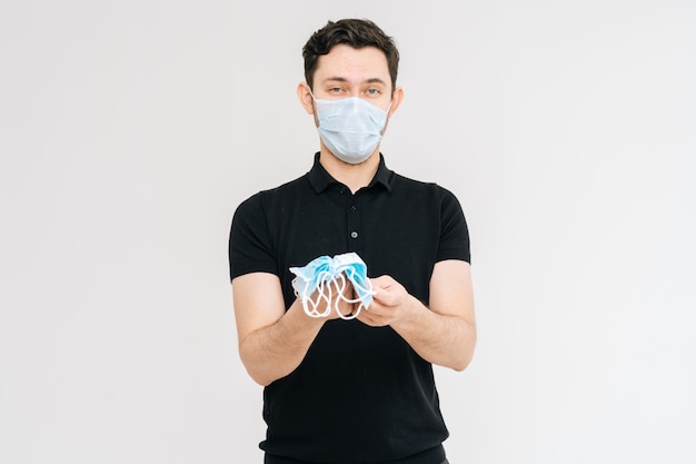 Prise de vue en studio d'un jeune homme portant un masque de protection tenant beaucoup de masques médicaux