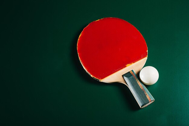 Prise de vue en studio d'une raquette de ping-pong et d'une balle posées sur une table de jeu verte