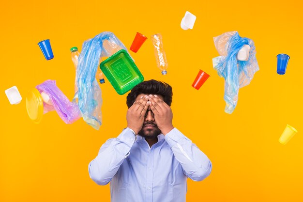 Problème de recyclage du plastique, écologie et concept de catastrophe environnementale - Un Indien a fermé les yeux avec les mains sur le mur jaune. Il est terrifié par les problèmes de déchets.