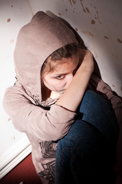 problèmes d'adolescents. fille solitaire, malheureuse et triste assise sur le sol dans un coin sombre et sale.