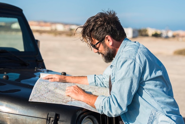 Problèmes de conduite Un homme conducteur perdu sur les routes utilise une ancienne carte de guide papier pour trouver la destination Personnes et transport mode de vie tourisme d'aventure Été campagne désert en arrière-plan Voyage