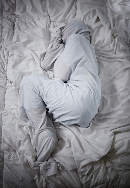 Les problèmes de santé mentale ne définissent pas qui vous êtes Photo d'un homme méconnaissable couché sous les couvertures dans un asile psychiatrique