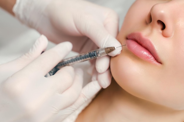 Procédure d'augmentation et de correction des lèvres dans un salon de cosmétologie, le spécialiste fait une injection