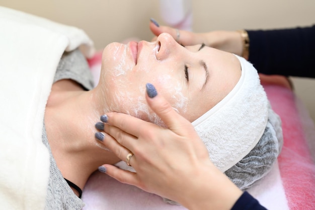 Procédure chez un cosmétologue nettoyant le visage des cosmétiques et préparant le visage pour le massage