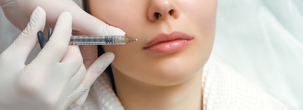 Procédure de correction de la forme des lèvres dans un salon de cosmétologie. Le spécialiste fait une injection sur les lèvres du patient. Augmentation des lèvres.