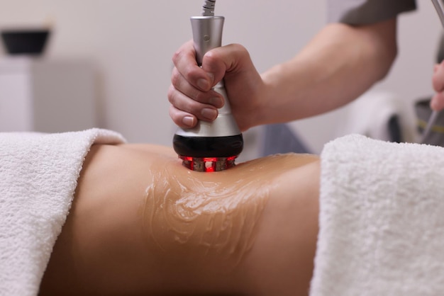 Procédure d'élimination de la cellulite sur l'abdomen féminin, massage du ventre par cavitation. Massage aux ultrasons pour perdre du poids. Correction de la figure féminine sans intervention chirurgicale. Gros plan du ventre.