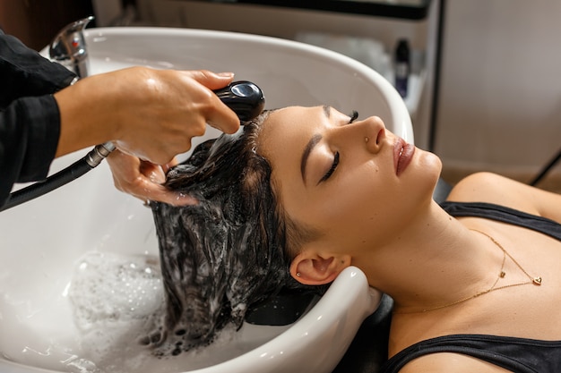 Procédure de lavage. Belle jeune femme avec coiffeur laver la tête au salon de coiffure.